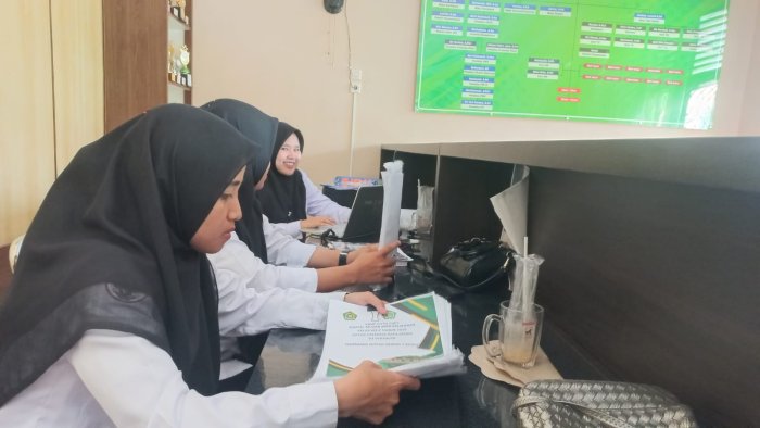 Staf Pengadministrasi MAN 2 Bungo Menjilid Bahan Administrasi Agar Tersusun Rapi